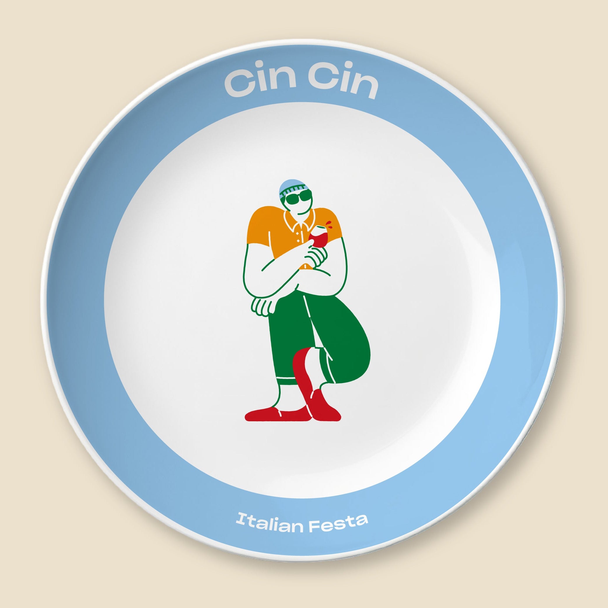 A round decorative plate with a white center, a light blue rim, and printed text reading 'Cin Cin' at the top and 'Italian Festa' at the bottom. The center features a stylized illustration of a person in an Italian flag color outfit holding a red rose.